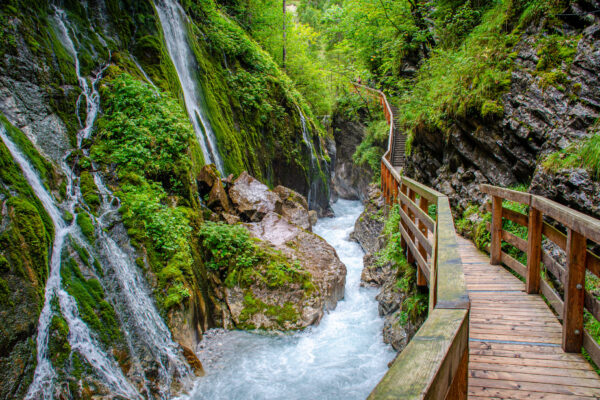 Wanderweg auf einem Holzsteg mit Wildwasser und Wasserfällen in der wildromantischen Wimbachklamm im Nationalpark Berchtesgaden